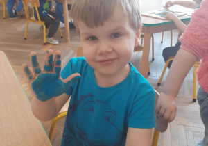 Chłopiec maluje dłoń na niebiesko